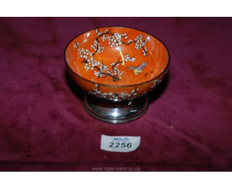 An enamel bowl in orange colour with enamel decoration of foliage and birds standing on a silver base hallmarked, Chester 192