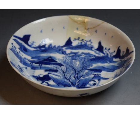 An 18th century circular dish, decorated in underglaze blue with bull, keeper, huts, mountains, trees and foliage, 15.5cm dia