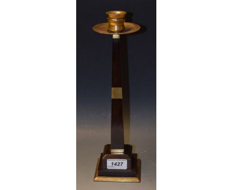 A French Art Deco rosewood table candlestick, in the style of Ruhlmann, brass sconce, spreading circular drip tray, tapering 