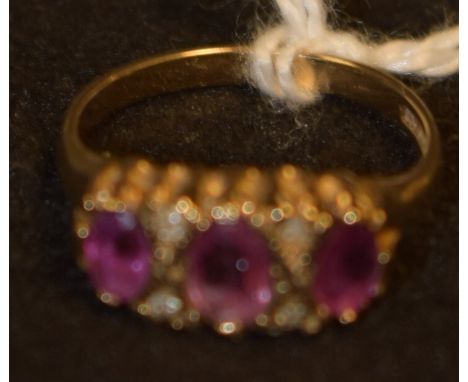 A pink spinel and diamond seven stone ring, set with three oval graduated pink spinels, each divided by a pair of round cut d