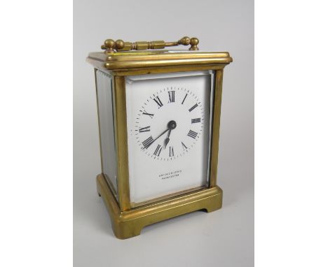 A brass encased carriage clock with white dial bearing Roman numerals &amp; inscribed Arnold &amp; Lewis, Manchester Conditio