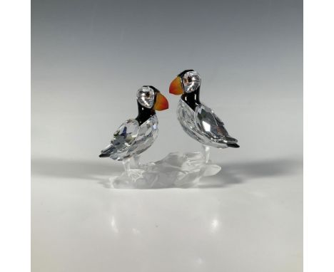 A precious clear and black cut crystal figure of two sweet puffins perched on a frosted rock, adorned with fire opal beaks an