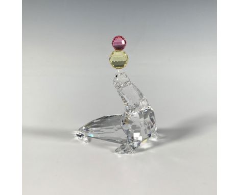 A cute faceted figure of a playful seal balancing pink and yellow balls on its nose. Part of the Cheerful Times series. Swaro