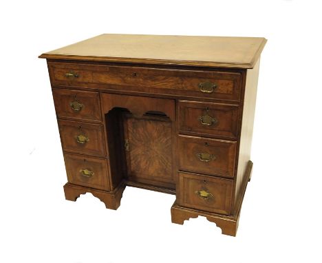 A George I style walnut kneehole desk, the single long drawer over two sets of three short drawers, flanking a cupboard door 
