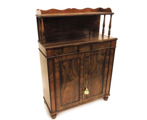 A William IV rosewood chiffonier, circa 1835, the panelled cupboard doors opening to reveal a shelved interior, below a singl