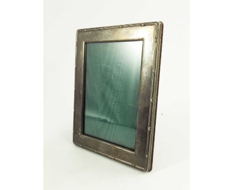 An Elizabeth II silver photo frame, Harrods, Sheffield 1994, ribbon and reed border, wooden easel back, opening 13cm x 9cm, 1