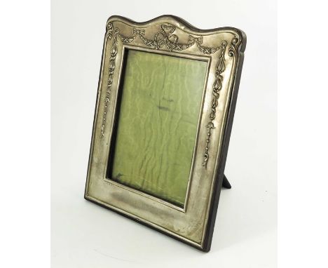 A large Edwardian silver photo frame, William Neale, Birmingham 1910, embossed with festoons and ribbons, ebonised easel back