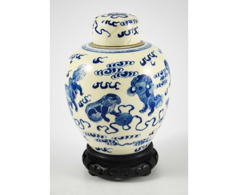 A Chinese blue and white ginger jar and cover, Kangxi mark, painted with dogs in clouds, on a hardwood base, ceramic 16cm hig