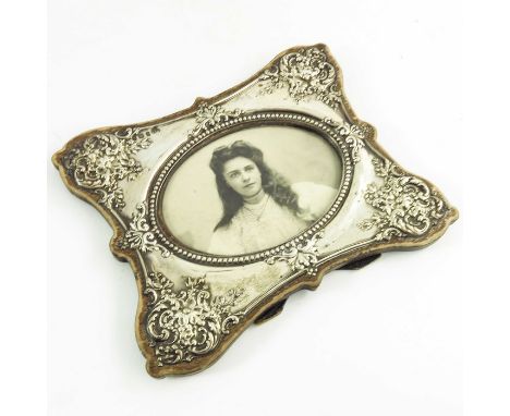 An Edwardian silver photo frame, W J Myatt, Birmingham 1905, shaped butterfly ogee form, embossed with floral scroll and hone