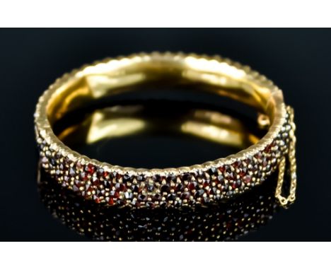 A Garnet Set Bangle, 20th Century, pave set with garnet stones, approximately 190mm in length, gross weight 30.5g Note: Metal