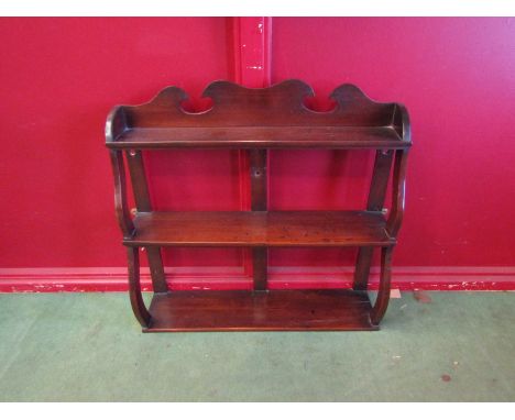 A 19th Century mahogany three tier wall hanging shelf with wavy supports and raised gallery back