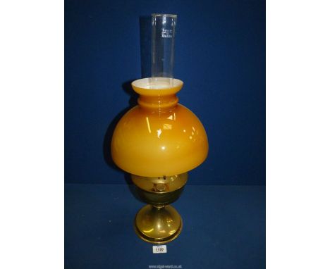 A brass oil lamp with amber glass shade and clear chimney, 23" tall.