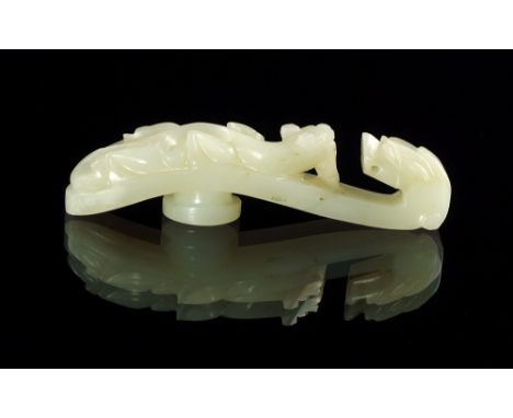 A Chinese pale green jade belt hook, 20th century, the terminal carved with a dragons head, with writhen dragon to the body, 