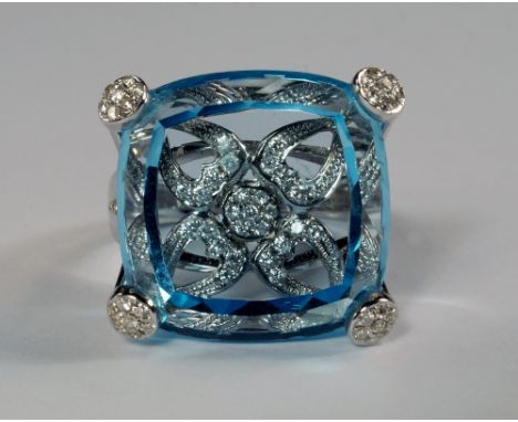 An unusual 18ct gold, blue stone and diamond set dress ring, the blue topaz colour stone of rounded square form with floret's