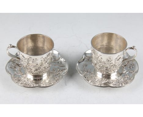 A pair of late 19th/early 20th Century Chinese export silver teacups and saucers, with applied floral, foliage, bird and inse