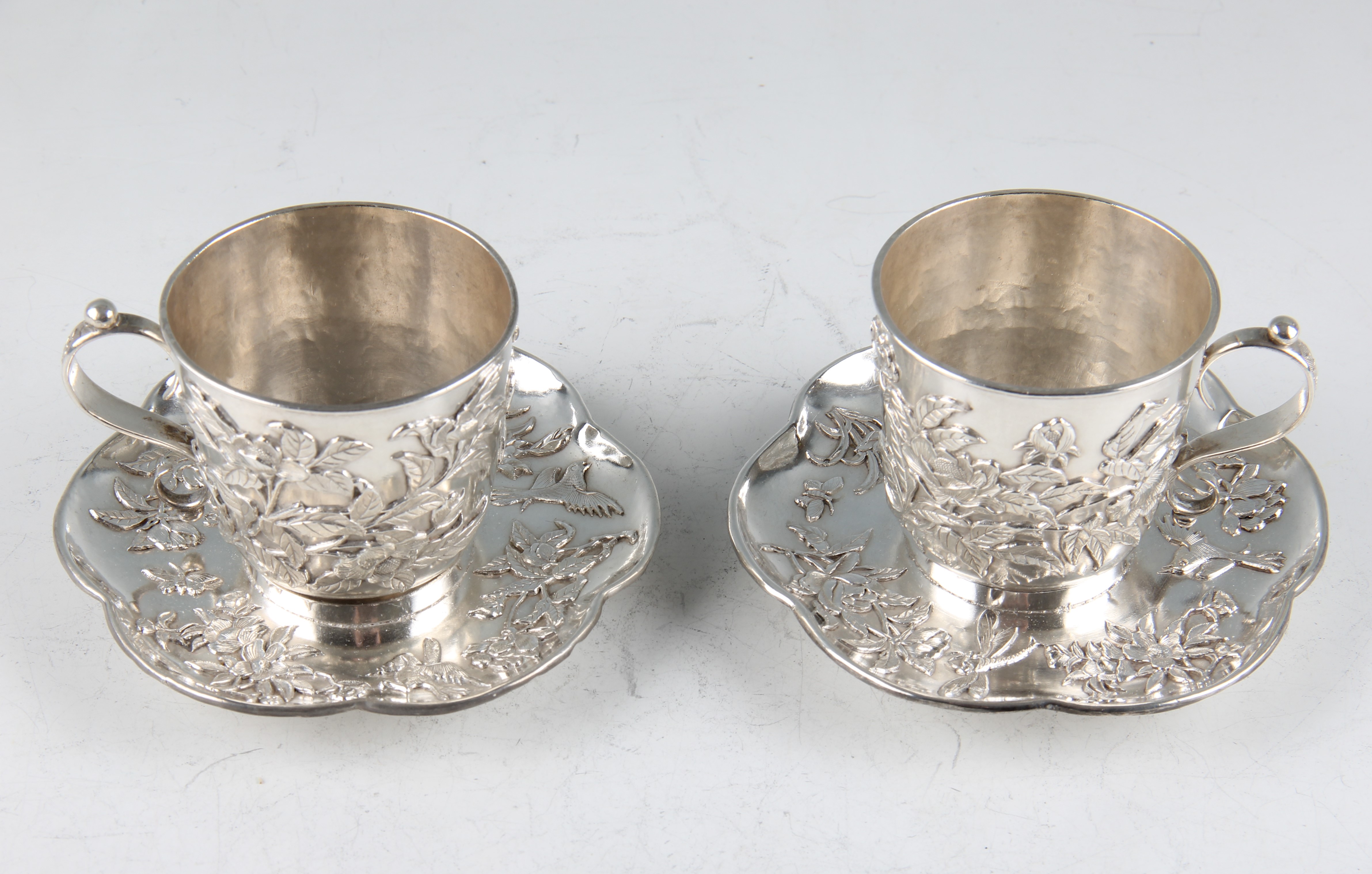 A pair of late 19th/early 20th Century Chinese export silver teacups and saucers, with applied fl