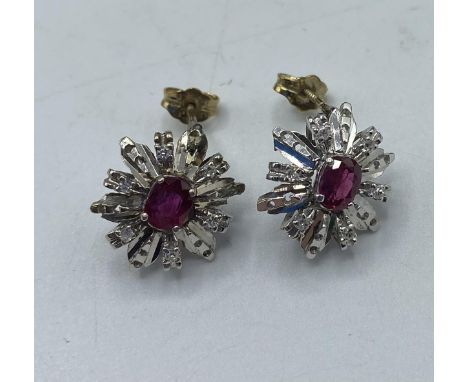 A pair of unmarked yellow and white metal earrings set with single oval free cut ruby with a single cut diamond surround. 4.7