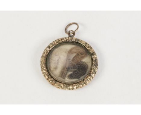 NINETEENTH CENTURY GOLD COLOURED METAL PENDANT, with engine turned front, chased border, glazed, scrolled hair locket back (t