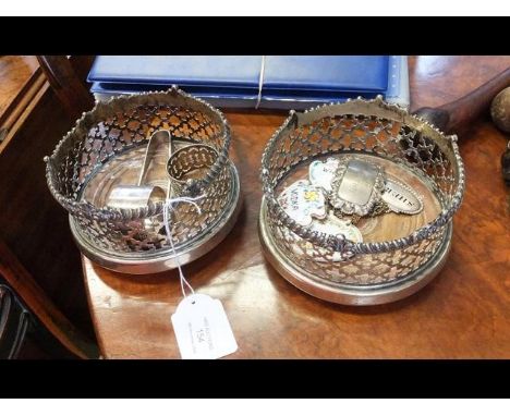 A pair of silver plated wine coasters on rollers together with wine labels, sugar tongs, napkin ring