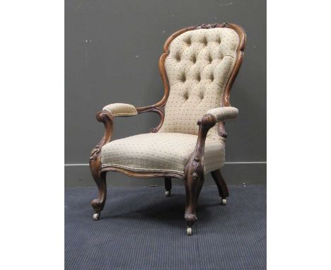 A late Victorian walnut button back arm chair on cabriole legs