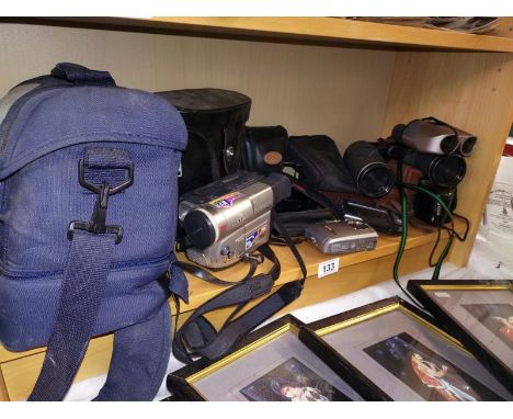 A shelf of cameras binoculars, phones etc.