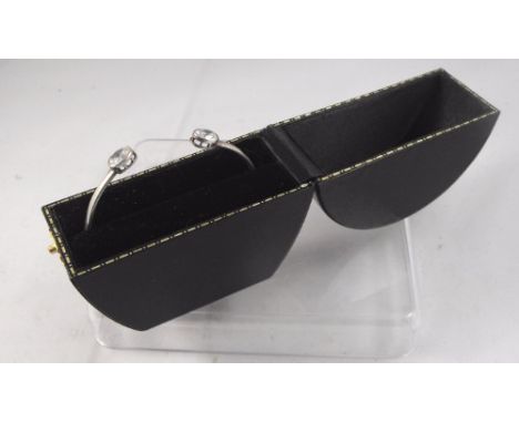 A white metal bangle set with two clear stones