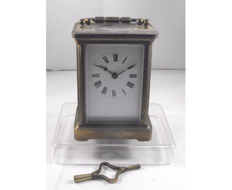 A brass carriage time piece with enamel dial having Roman Numerals 11cm high 