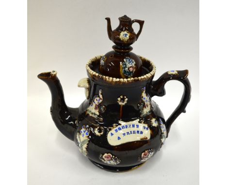 A Victorian barge ware teapot, treacle glaze decorated with moulded birds and flowers and a band inscribed 'A Present to a Fr