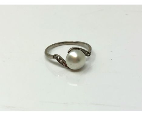 An early twentieth century platinum ring set with a pearl and diamond shoulders, size I.