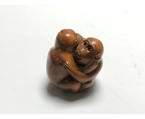 A carved Chinese hardwood netsuke - Two monkeys embracing