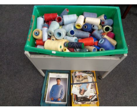 A box on a metal trolley containing a quantity of cotton spools together with two trays containing vintage knitting patterns 