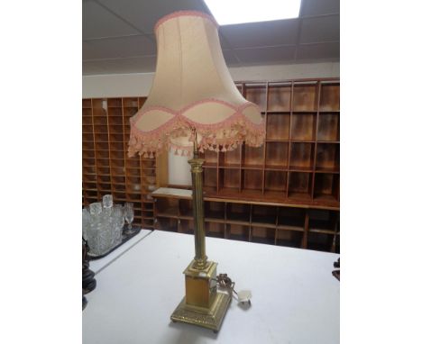 A brass Corinthian column table lamp with pink tasseled shade  