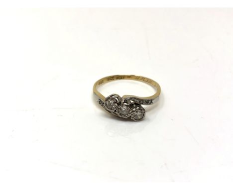 An 18ct gold and platinum three stone diamond crossover ring, size S1/2.  CONDITION REPORT: 3.4g