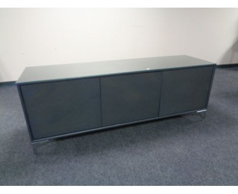 A contemporary triple door low sideboard with plate glass top, on chrome legs 