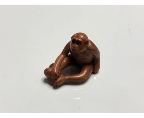 A carved Chinese hardwood netsuke - Monkey with fruit