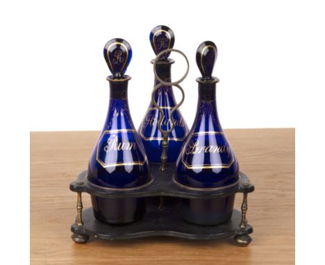 Three Bristol blue bottlesin papier mache stand/tantalus, on bun feet, 'Rum', 'Brandy' and 'Hollands', with gilt highlighted 
