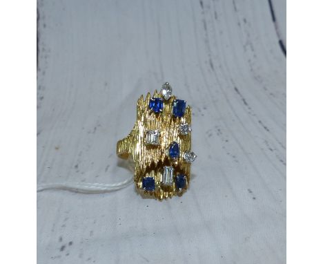 A 1970's lady' dress ring set with diamonds and sapphires in a variety of cuts, on tubular bark effect shank, 13.9 gm gross, 