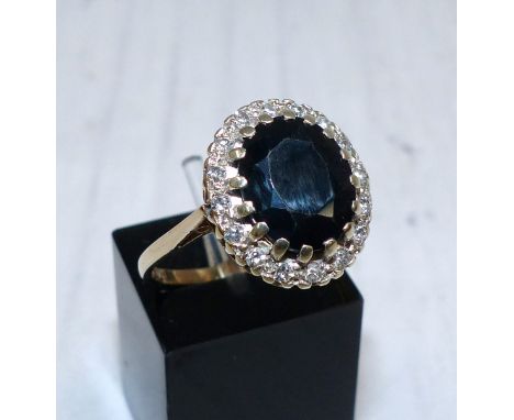 A 9 carat hallmarked gold diamond and sapphire ring, the oval sapphire surrounded by 15 diamonds, 4.1 gm