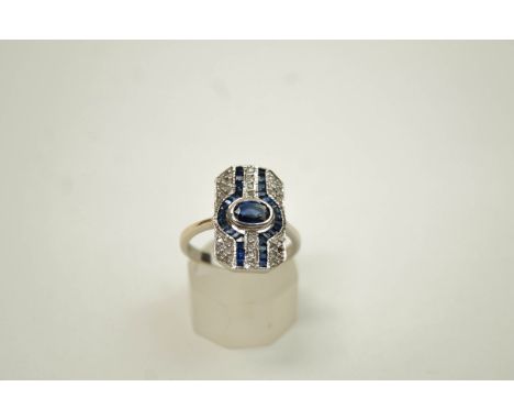 An Art Deco style 18 carat white gold, sapphire and diamond panel ring, centred with an oval mixed-cut sapphire within calibr