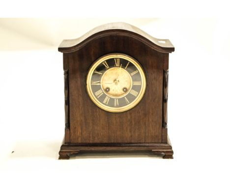 A 20th Century mahogany cased mantel clock with a French eight day movement, black dial with Roman numerals on bracket feet, 
