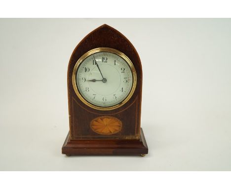 An Edwardian inlaid mahogany mantel clock, with an arched top and white enamel dial on brass bun feet, 21cm high.
