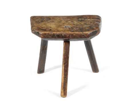 A GEORGE III VERNACULAR ELM MILKING STOOLLATE 18TH / EARLY 19TH CENTURYon rustic tripod supports34.5cm high, 37.2cm wide
