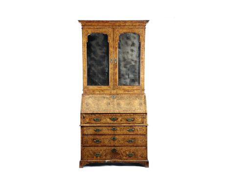 A GEORGE II WALNUT BUREAU BOOKCASEC.1730with cross and feather banding, the cavetto cornice above a pair arched bevelled mirr