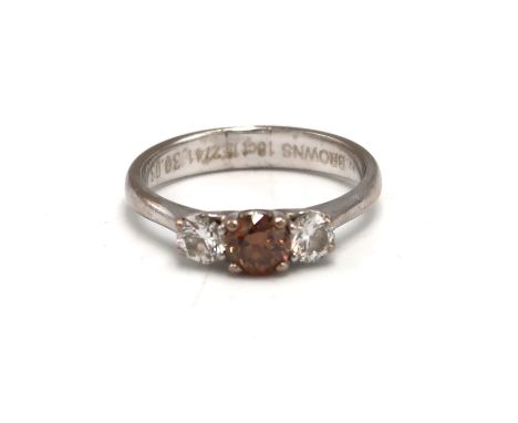 An 18ct white gold and diamond three stone ring, the central fancy cognac coloured stone of approximately 0.5ct, flanked by t
