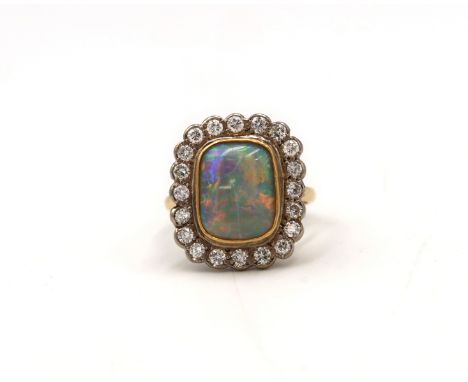 A black opal and brilliant cut diamond cluster ring. Opal approximately 13.5mm by 11mm, vibrant play of colour, some crazing.