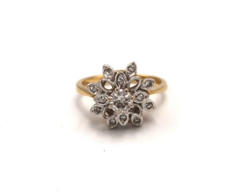 An 18ct gold and diamond cluster ring with flower head design, with illusion set central, round cut, diamond of approximately
