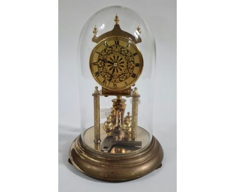 A revolving pendulum clock under glass dome, with key. 