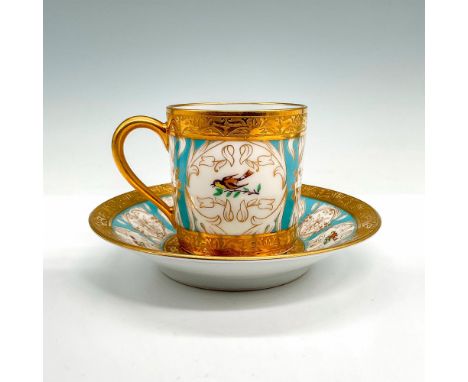 An opulent demitasse cup and saucer set exhibiting regal encrusted gold-tone trim, embossed floral designs, light blue design