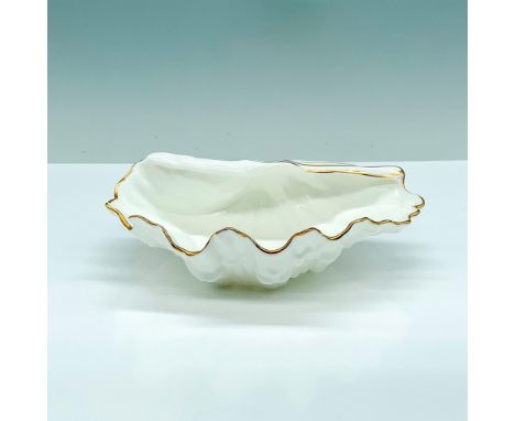 A white trinket box in the shape of half of an oyster shell with gold-colored line accents around the borders. Wedgwood backs