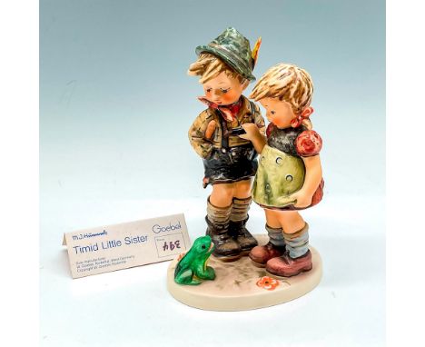 Brother and sister figural looking down at a frog. Dressed in traditional dress, colored in browns, sage, red and orange. Goe